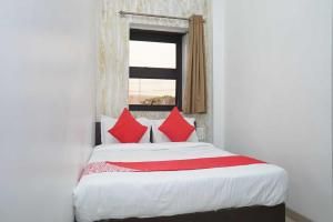 a bedroom with a bed with red pillows and a window at OYO Flagship 81100 Hotel Sai Lodging in Māngvādi