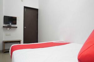 a bedroom with a red and white bed and a television at OYO Flagship 81100 Hotel Sai Lodging in Māngvādi