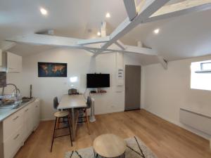a kitchen with white cabinets and a table and a tv at Centre Historique - Charmant T3 - 1h de l Océan in Orthez +2 photos