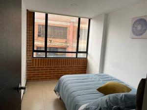 a bedroom with a bed and a window at Moderno apartamento cerca al aeropuerto in Bogotá