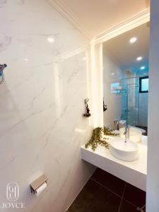 bagno bianco con lavandino e specchio di Joyce Boutique Coffee & Stay a Da Lat