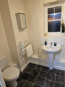 een badkamer met een wastafel, een toilet en een raam bij 3/4 bedrooms, Free Parking, Wifi, Home away from home feel in Purfleet
