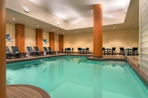 una piscina en una habitación de hotel con sillas y mesas en The Lincoln Marriott Cornhusker Hotel, en Lincoln