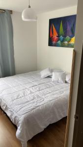 1 cama blanca en un dormitorio con una pintura en la pared en HABITACION DOBLE con baño compartido en apartamento compartido, en Bucaramanga