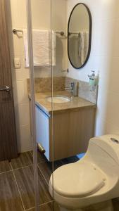uma casa de banho com um WC, um lavatório e um espelho. em HABITACION DOBLE con baño compartido en apartamento compartido em Bucaramanga