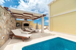 eine Terrasse mit einem Pool und Stühlen sowie ein Haus in der Unterkunft Holiday house with a swimming pool Prizba, Korcula - 199 in Prizba