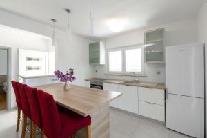 eine Küche mit weißen Schränken und einem Holztisch mit roten Stühlen in der Unterkunft Holiday house with a swimming pool Prizba, Korcula - 199 in Prizba