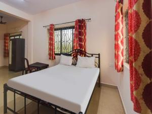 a bedroom with a white bed and a window at OYO Flagship 81094 Bay Breeze Hotel in Baga