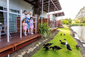 een groep kinderen die op een veranda naar eenden staan te kijken bij Tall Timbers Tasmania in Smithton