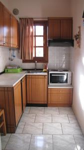 cocina con armarios de madera y microondas en Rafaela House, en Milina