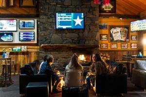 un groupe de personnes assises dans un bar avec une cheminée dans l'établissement Tall Timbers Tasmania, à Smithton