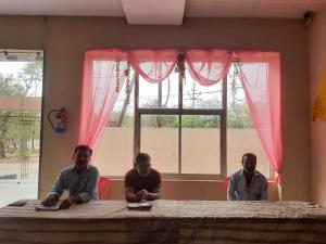 three men sitting at a table in front of a window at OYO 81141 Mangal Bhawan in Kānpur