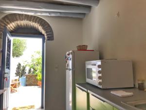 een keuken met een koelkast en een magnetron op een aanrecht bij The Walnut Tree - Cycladic Getaway with Sea Views in Lámira