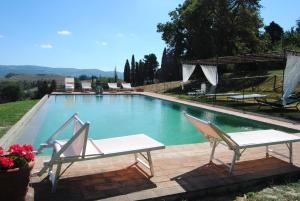 a swimming pool with two chairs and a table at La Fonte Carducciana in San Casciano dei Bagni