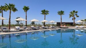 una piscina con sillas y palmeras en InterContinental Residences Abu Dhabi, an IHG Hotel, en Abu Dabi