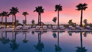 uma piscina com cadeiras e palmeiras ao pôr-do-sol em InterContinental Residences Abu Dhabi, an IHG Hotel em Abu Dhabi