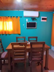 a dining room table with three chairs and a television at El refugio Anillaco in Anillaco