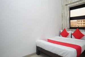 a bedroom with two beds with red pillows and a window at OYO Flagship 81100 Hotel Sai Lodging in Māngvādi