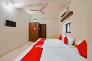 a bedroom with a large white bed with red pillows at Casa Paradiso in Panaji