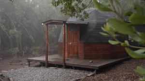 a small wooden cabin with a deck in the woods at Lircaydomohostal - Domo 40m2 para 4 personas in Talca