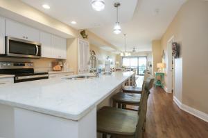 a kitchen with a large white counter top and chairs at Club at Mexico Beach 2D in Mexico Beach