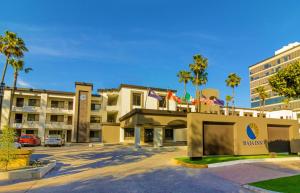 a hotel with palm trees in a parking lot at Baja Inn Hoteles Rio in Tijuana