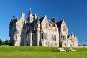 un vecchio castello con due panchine davanti di Glengorm Castle a Tobermory