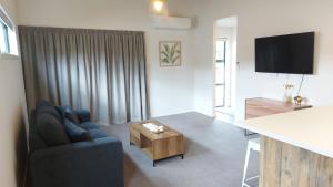 un soggiorno con divano blu e tavolo di Sleek Suite by the Sand (1 bedroom) a Dunedin