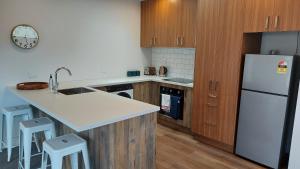 una cucina con frigorifero bianco e armadietti in legno di Sleek Suite by the Sand (1 bedroom) a Dunedin