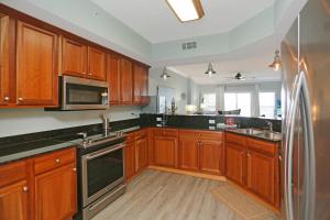 kuchnia z drewnianymi szafkami i lodówką ze stali nierdzewnej w obiekcie Paradise Shores 302 Serenity Shores by Pristine Properties Vacation Rentals w mieście Mexico Beach