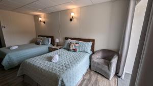um quarto de hotel com duas camas e uma cadeira em Motel Gentilhommière em Saint-Siméon