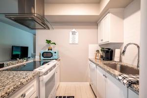 a kitchen with white cabinets and a sink and a microwave at 1 Galleria Downtown 3BR- Free Parking in Houston