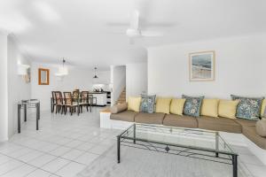 ein Wohnzimmer mit einem Sofa und einem Tisch in der Unterkunft Belle Escapes Poolview Suite 77 Alamanda Resort Palm Cove in Palm Cove