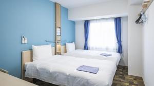 two beds in a room with blue walls and a window at Toyoko Inn Nagano-eki Higashi-guchi in Nagano