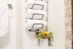 a stack of towels on a wall with a vase of flowers at Bee our Guest! SLC Cozy Beehive in Salt Lake City