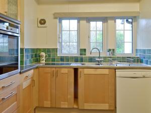 a kitchen with a sink and two windows at Green Hedges in Budleigh Salterton