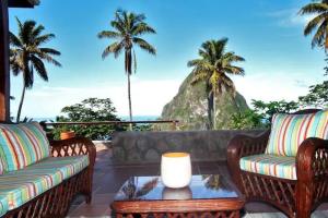 a patio with a view of the ocean and palm trees at TheTerrace -$1Mil Piton View in Soufrière