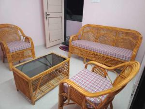 three wicker chairs and a table and a mirror at OYO HOME 81185 Srinivas Service Home in Rājahmundry