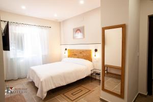 a bedroom with a white bed and a mirror at Hotel Rural el Turuñuelo 