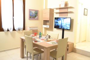 una sala da pranzo con tavolo, sedie e TV di Appartamenti Palazzotto a Stresa