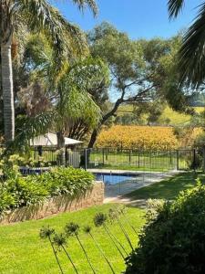 a pool in a garden with a fence and trees at Amande Bed and Breakfast in McLaren Vale