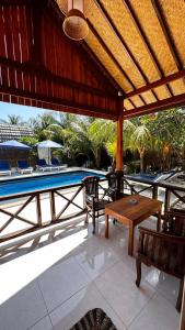 a patio with a table and chairs and a pool at Hakuna Matata Resort Gili Air in Gili Air