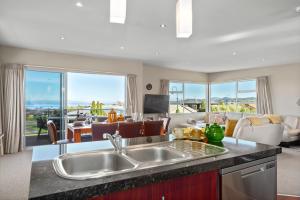 a kitchen with a sink and a living room at The Lakehouse - Taupo in Taupo