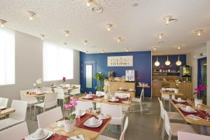 ein Restaurant mit Tischen und weißen Stühlen und eine Küche in der Unterkunft Séjours & Affaires Massy Atlantis in Massy