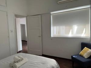 1 dormitorio con cama, ventana y silla en Dpto en el centro de Mendoza en Mendoza