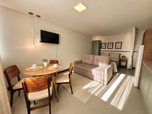 sala de estar con mesa y sofá en Residence Farol - Loft 204, en Laguna