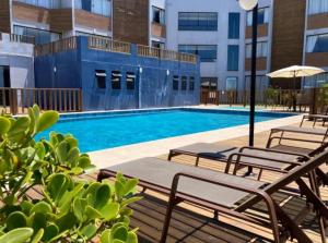 uma piscina com cadeiras e um guarda-sol num edifício em Residence Farol - Loft 204 em Laguna