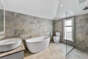 a bathroom with a large white tub and a toilet at Robe Beach Stays in Robe +22 photos