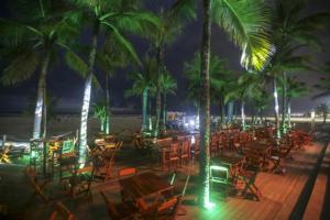 a deck with chairs and palm trees at night at Sol & Mar Hostel in Praia Grande
