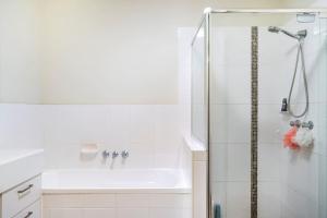a white bathroom with a shower and a sink at Private Room with Separate Bath in Shared Accommodation in Redcliffe